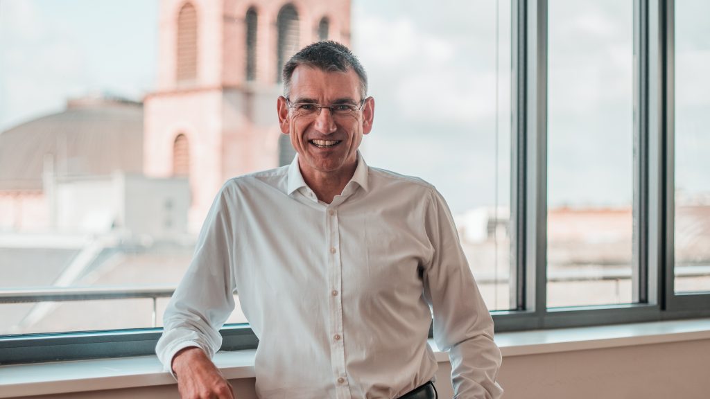 Porträtbild von Stefan Schwärzler, CEO von Senzavi, der vor einem Fenster steht und lächelt.